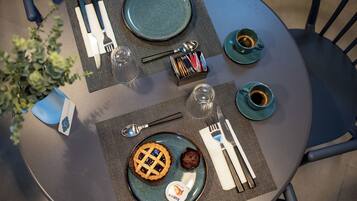 Una mesa dispuesta con un plato de comida, cubiertos y dos tazas de café.