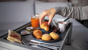 Una bandeja con cruasanes, un vaso de jugo de naranja, un pequeño recipiente de Nutella y una porción de mantequilla.