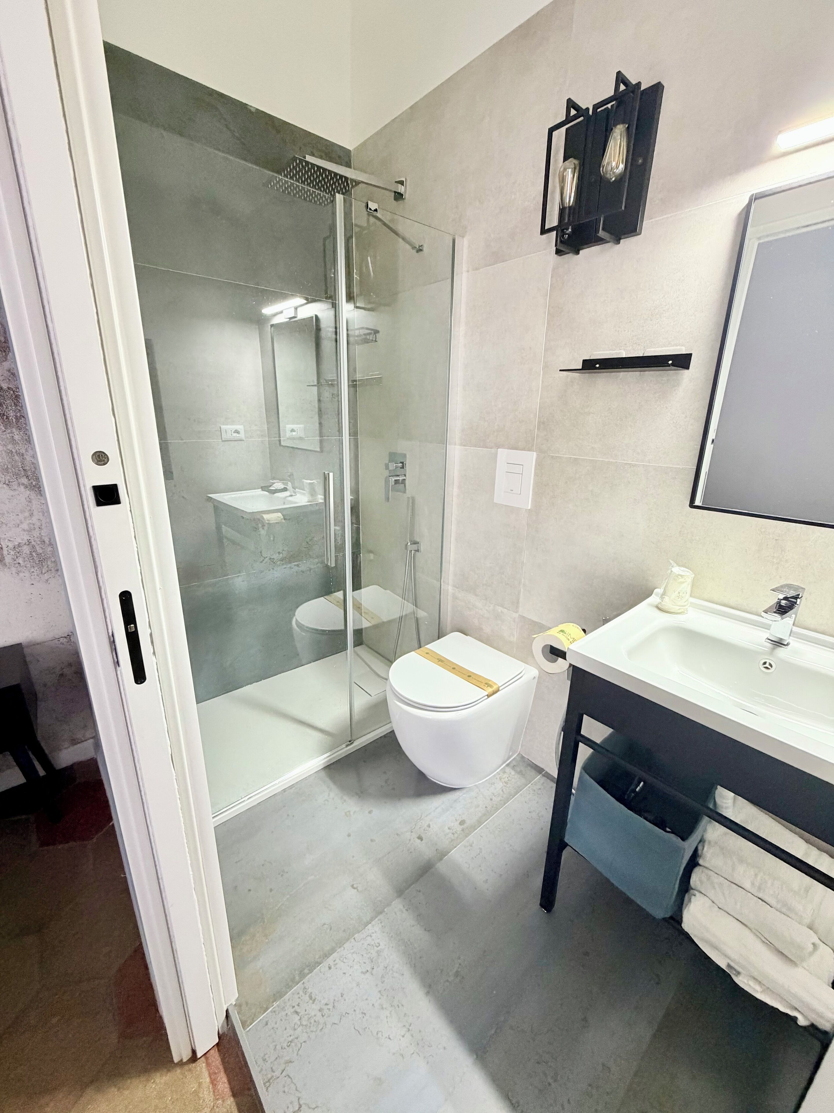 Une salle de bain moderne avec une douche à parois de verre, des toilettes blanches et un lavabo avec un miroir au-dessus.