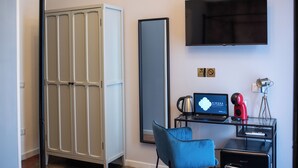 A hotel room with a wardrobe, a desk with a laptop, a chair, a coffee maker, and a television. - Dimora San Lorenzo (Taranto)