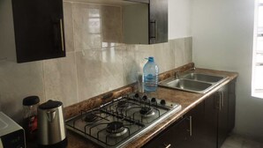 A kitchen with a gas stove, a sink, and cabinets. - ROOMS & SUITES (Monterrey)