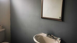 A bathroom with a white sink, a mirror, and a toilet. - ROOMS & SUITES (Monterrey)