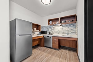 Una cocina moderna con un refrigerador de acero inoxidable, armarios de madera, un microondas y un lavavajillas.