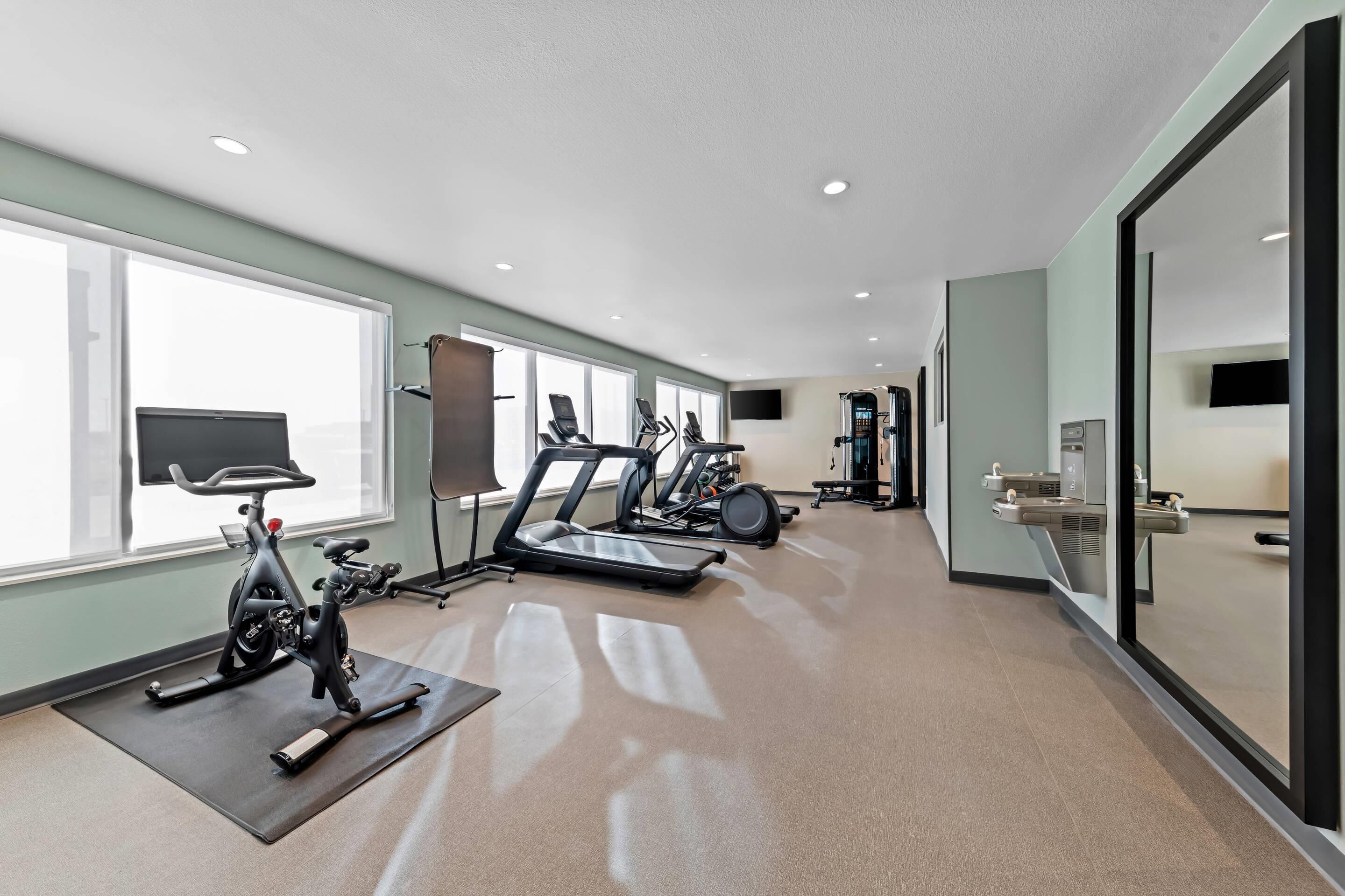 A gym with exercise equipment, large windows, and a modern design.