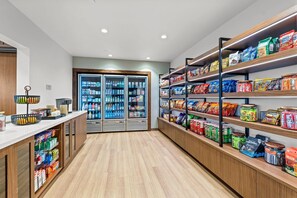 A clean, well-organized snack and beverage section with refrigerated drinks and shelves stocked with various packaged goods. - Everhome Suites Waco by Choice Hotels (Waco)