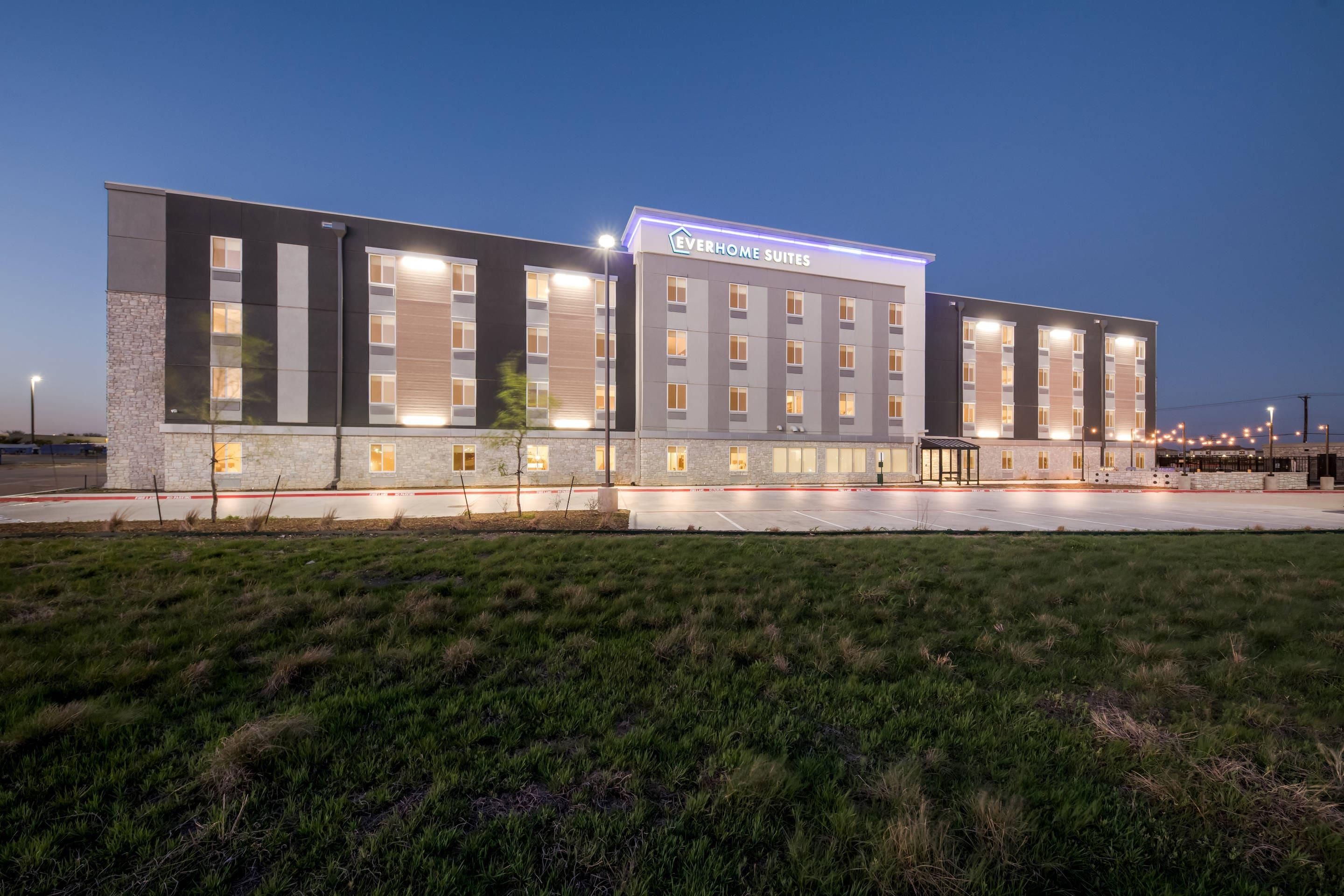 A modern hotel with a flat roof, large windows, and a sign reading "Everhome Suites."