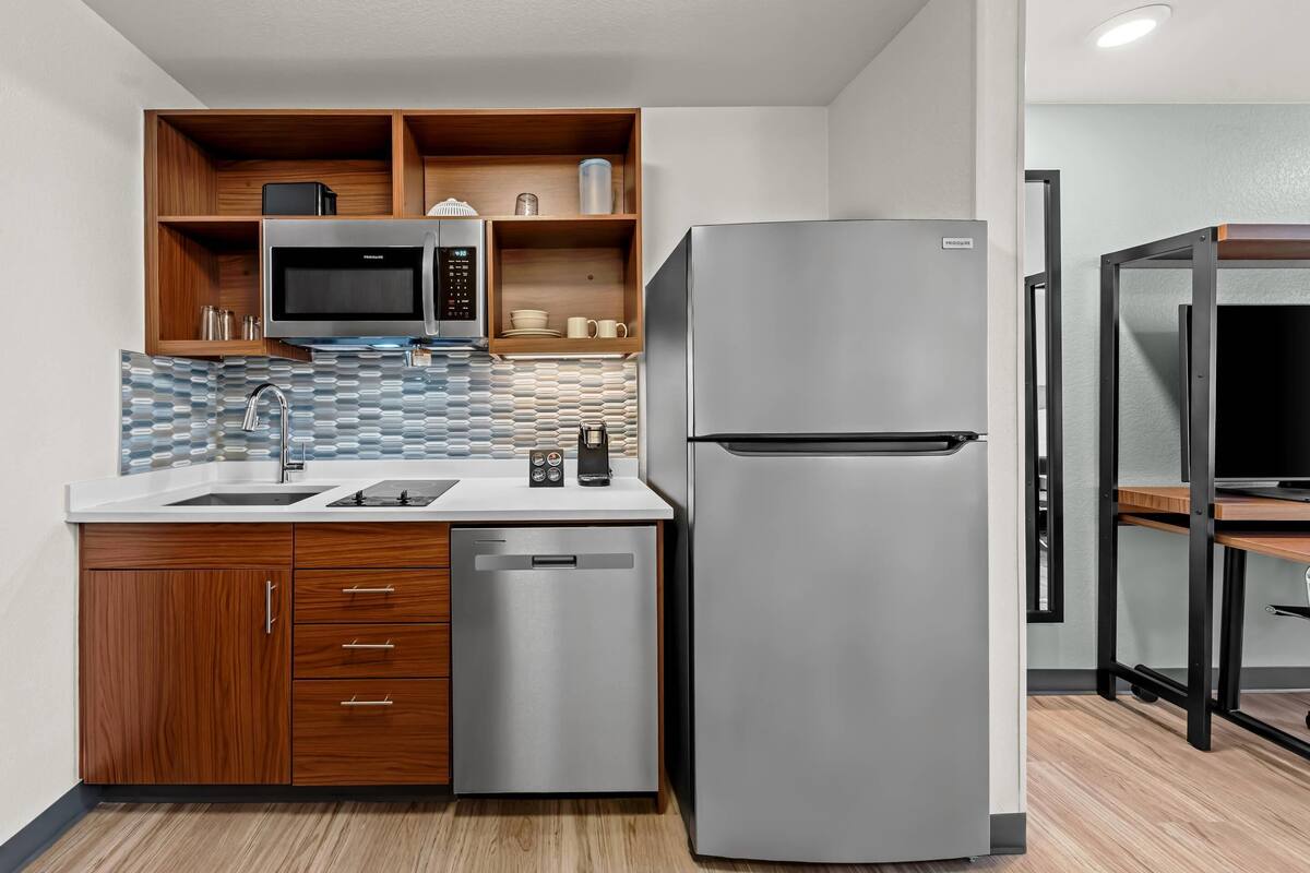 A compact kitchen with a stainless steel refrigerator, a microwave, and a dishwasher.