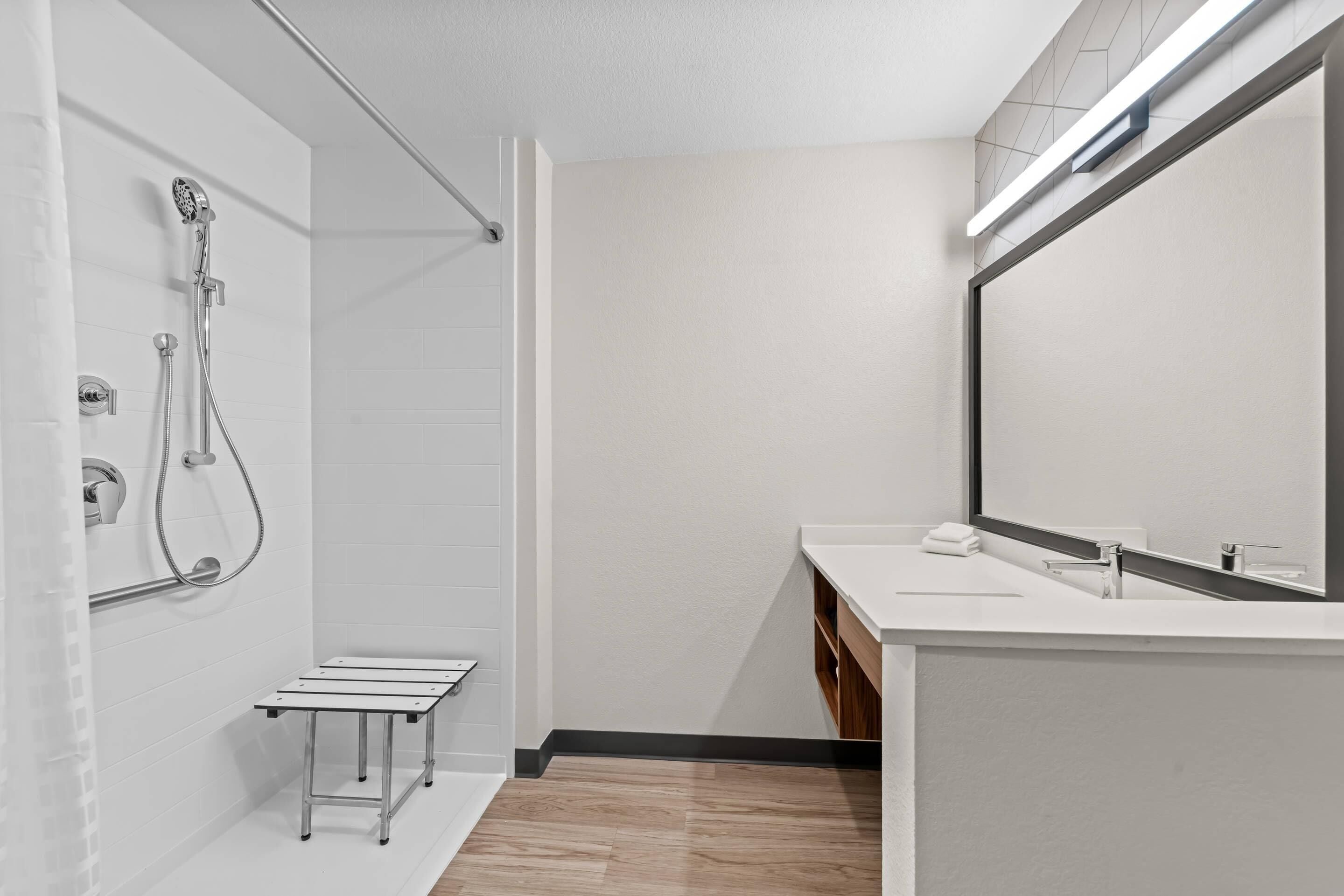 A modern bathroom with a shower, a sink, and a mirror.