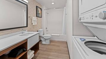 A modern bathroom with a sink, toilet, shower, and a built-in washing machine.