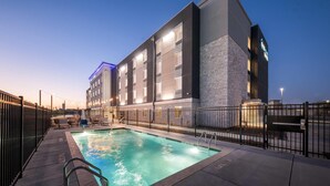 A modern hotel with a swimming pool, outdoor seating, and a stone facade. - Everhome Suites Waco by Choice Hotels (Waco)