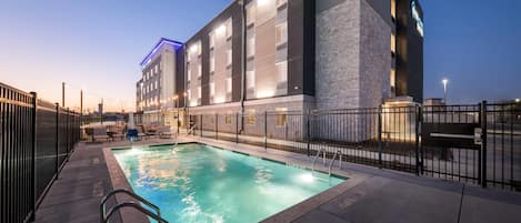 Un hotel moderno con piscina, zona de estar al aire libre y fachada de piedra.