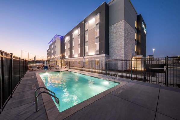 A modern hotel with a swimming pool, outdoor seating, and a stone facade. - Everhome Suites Waco by Choice Hotels (Waco)