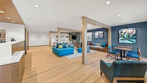 A spacious lobby with a reception desk, blue sofas, wooden flooring, and a modern ceiling design. - Everhome Suites Waco by Choice Hotels (Waco)