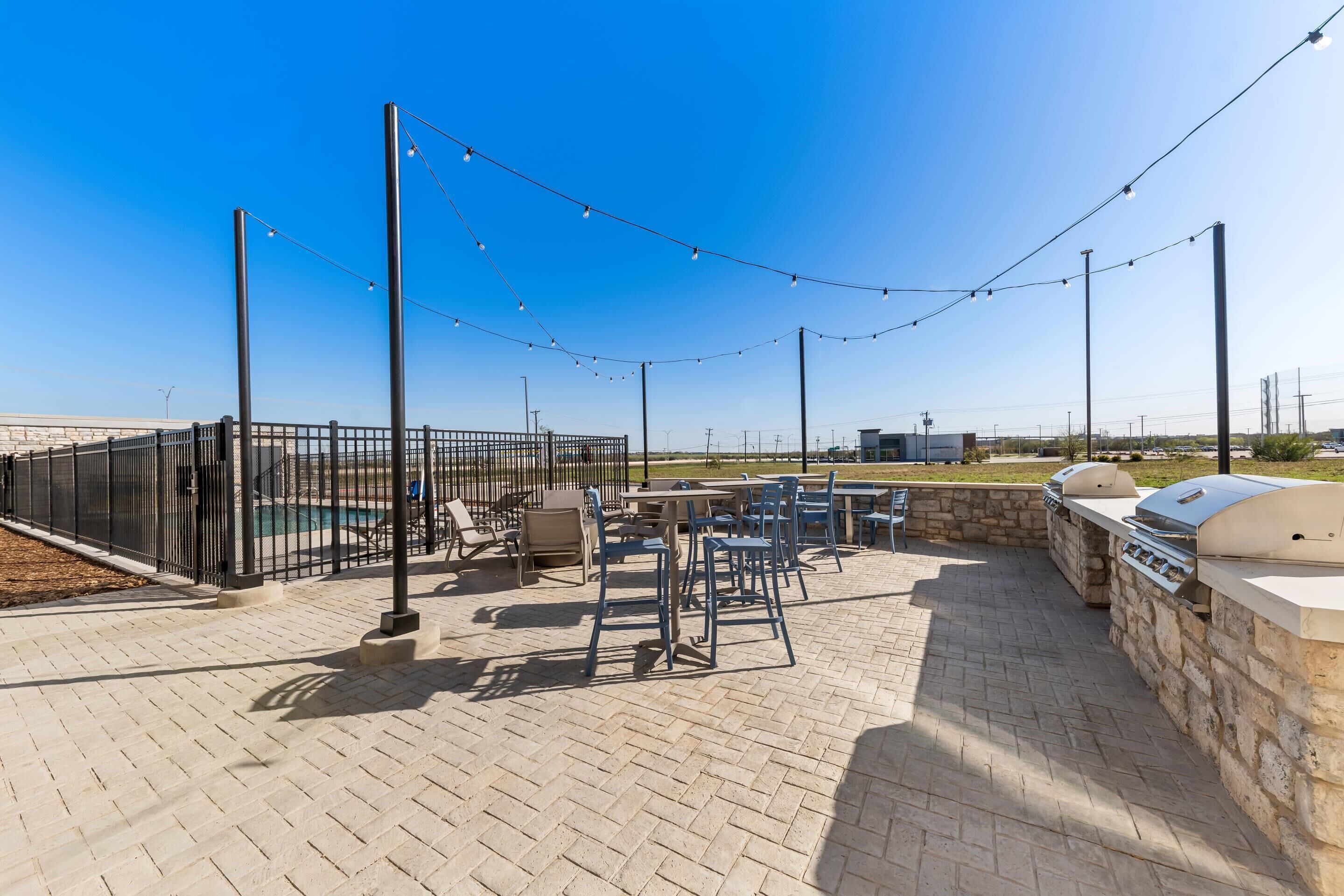 Eine Außenpatio-Terrasse mit Pool, Grill und Sitzgelegenheiten.