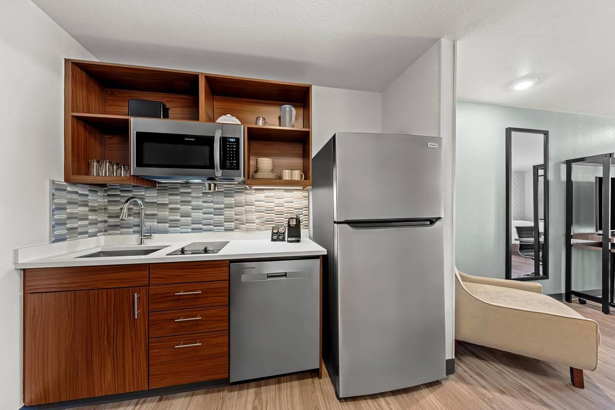 A compact kitchen with a microwave, refrigerator, and wooden cabinets.