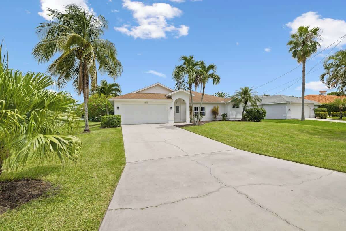 A single-story house with a front yard and palm trees.