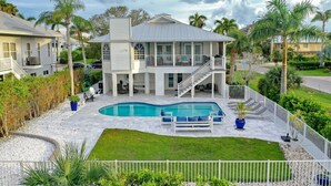 Ein zweistöckiges Haus mit Swimmingpool, überdachter Terrasse und umzäunter Garten.
