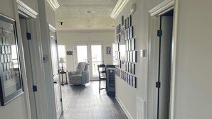A spacious hallway with a dark wood floor, white walls, and a ceiling with recessed lighting. - LAKE HOUSE. Serene, charming 5-bedroom house in greater New Orleans. (New Orleans)
