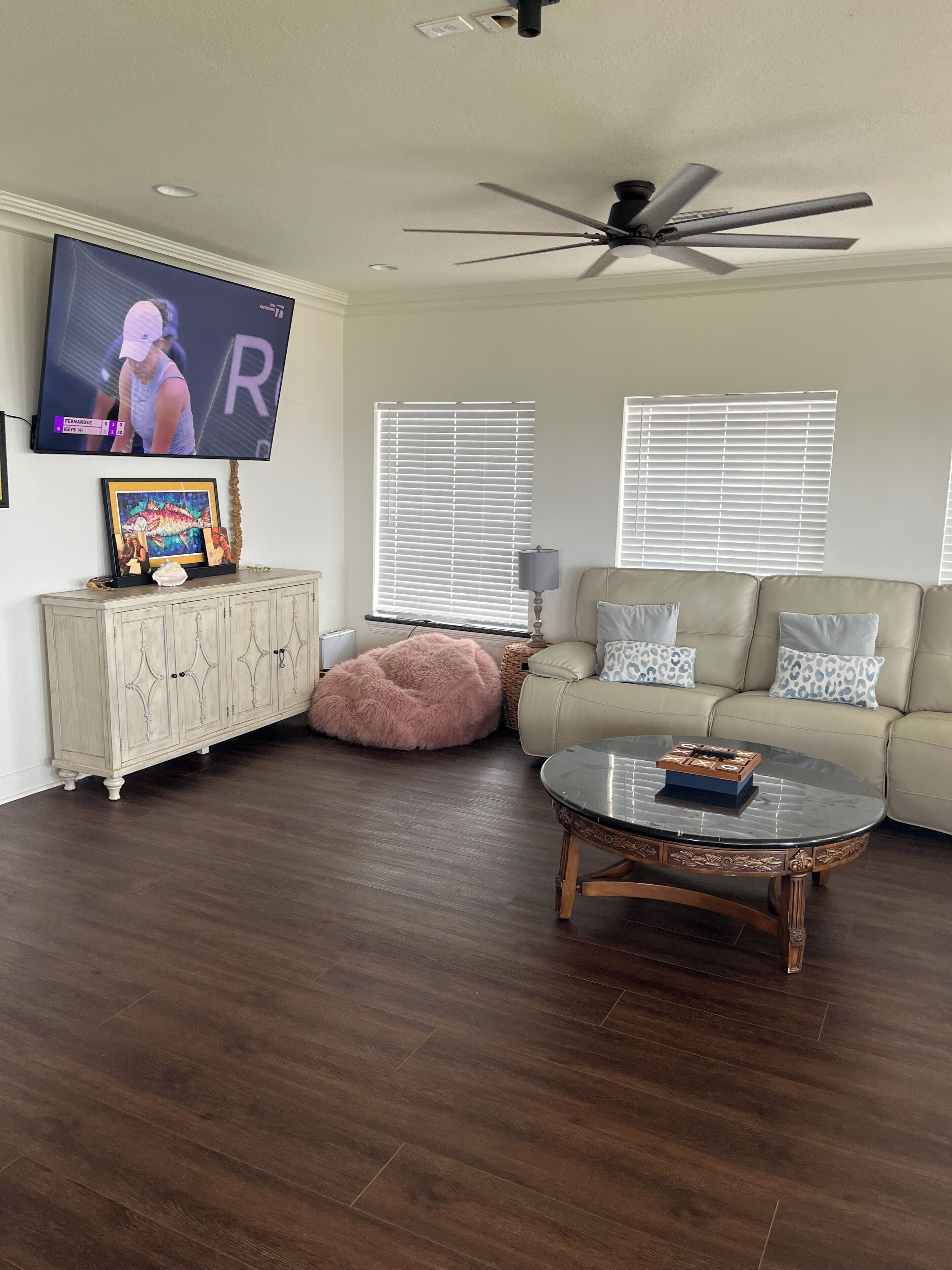 Ein Wohnzimmer mit Fernseher, Deckenventilator, Sofa und Couchtisch.