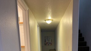 Un corridoio con pavimento in legno, pareti bianche e una luce al soffitto.