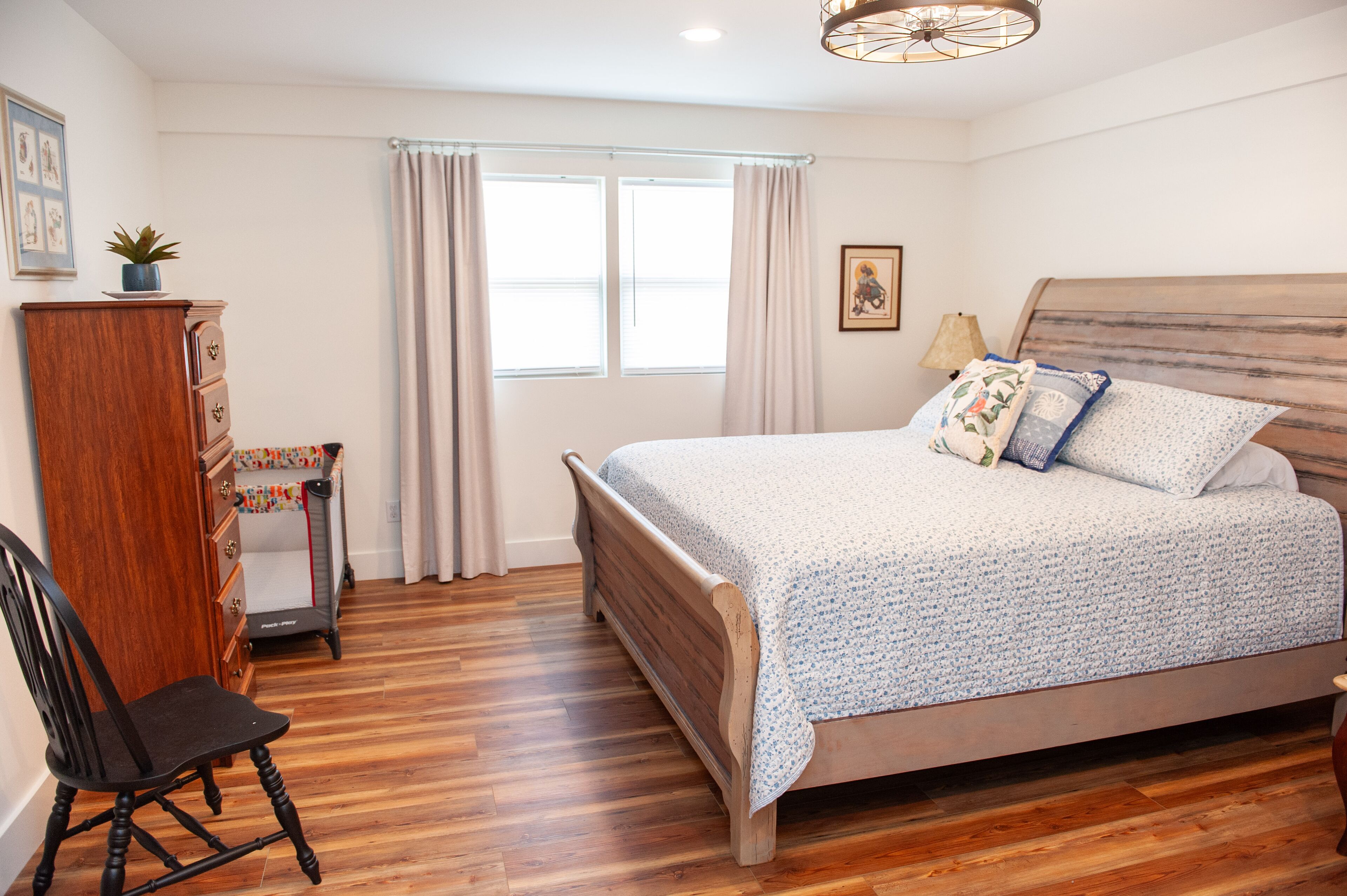 Un dormitorio con cama de madera, escritorio, silla y ventana con cortinas.