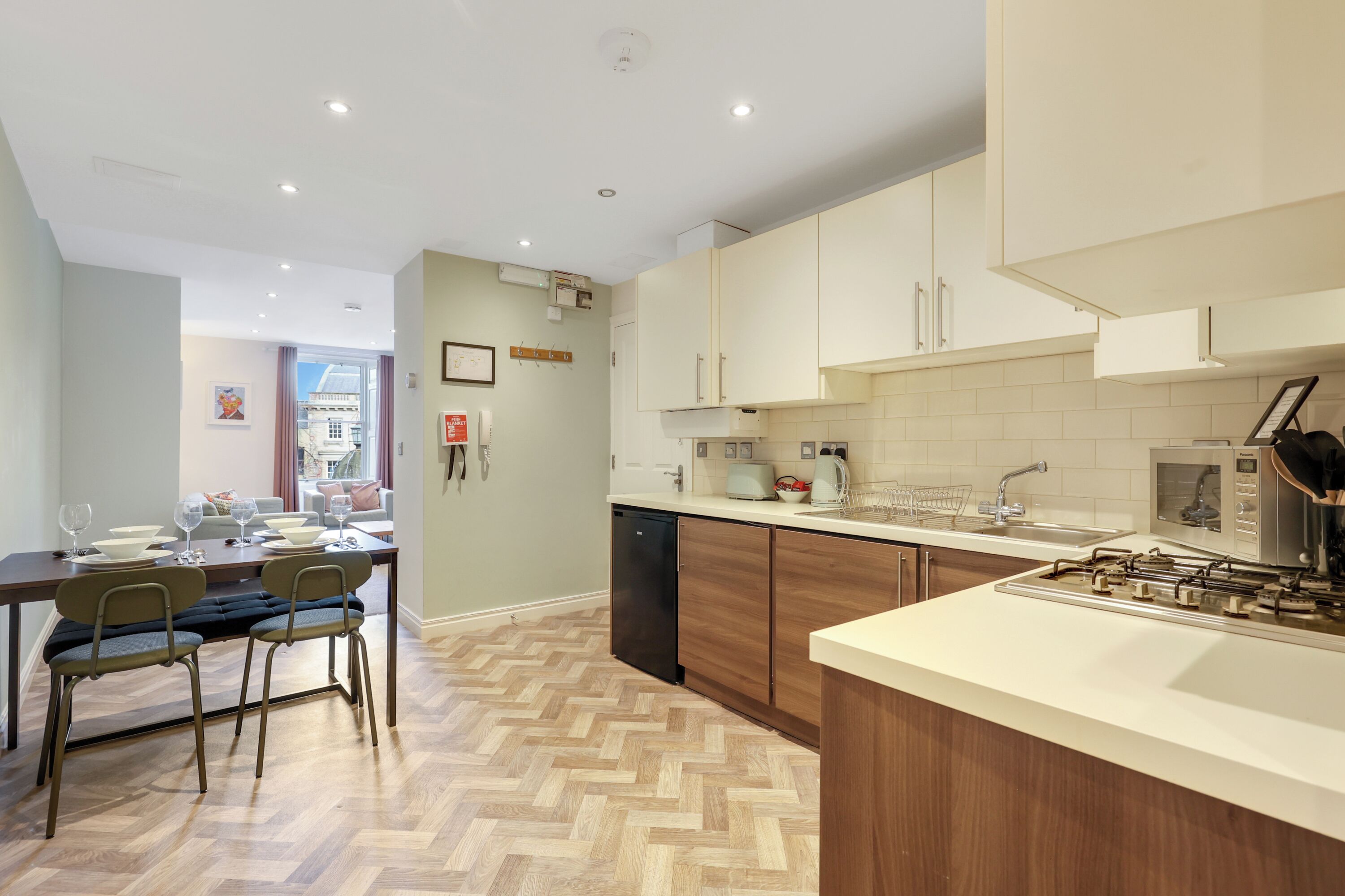 Una cocina moderna con armarios de madera, estufa empotrada y comedor con suelo de espiga.