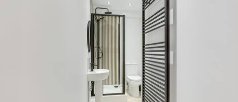 A modern bathroom with a shower, toilet, and sink.