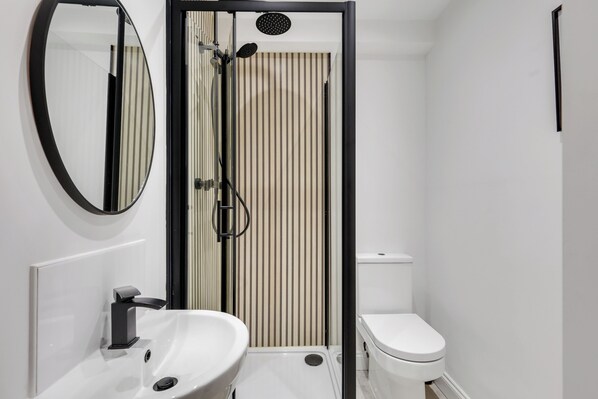 A modern bathroom with a white sink, a toilet, a shower with a black frame, and a mirror. - Earl Grey - North East Escapes (Alnwick)
