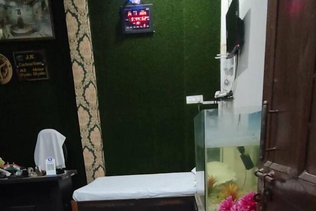 Une pièce comprenant un lit, une petite table, un vase décoratif et une horloge fixée au mur.