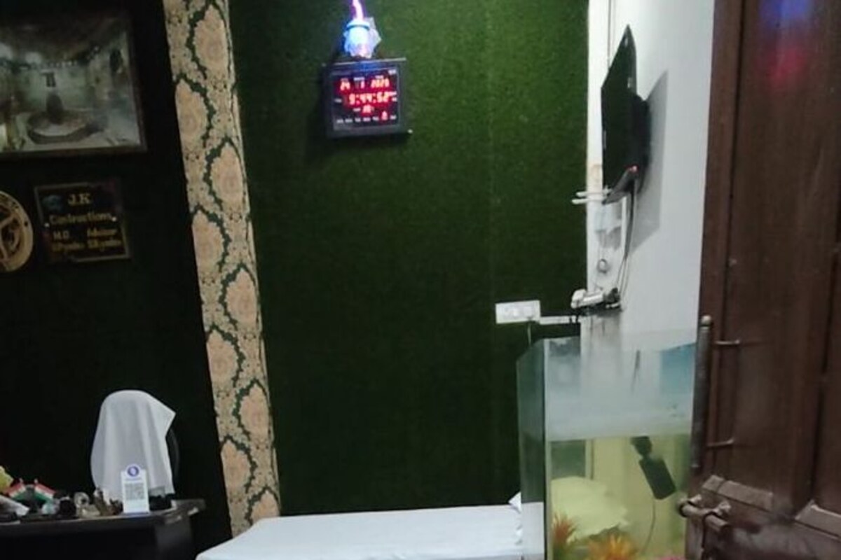 Une pièce comprenant un lit, une petite table, un vase décoratif et une horloge fixée au mur.