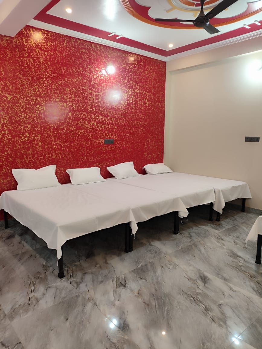 A room with two beds, a red textured wall, and a ceiling fan.