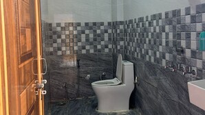 Un baño con inodoro, ducha y un balde verde.
