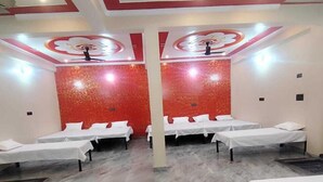 Una habitación de hotel con cuatro camas dispuestas en fila, una pared de acento roja y suelo de mármol.