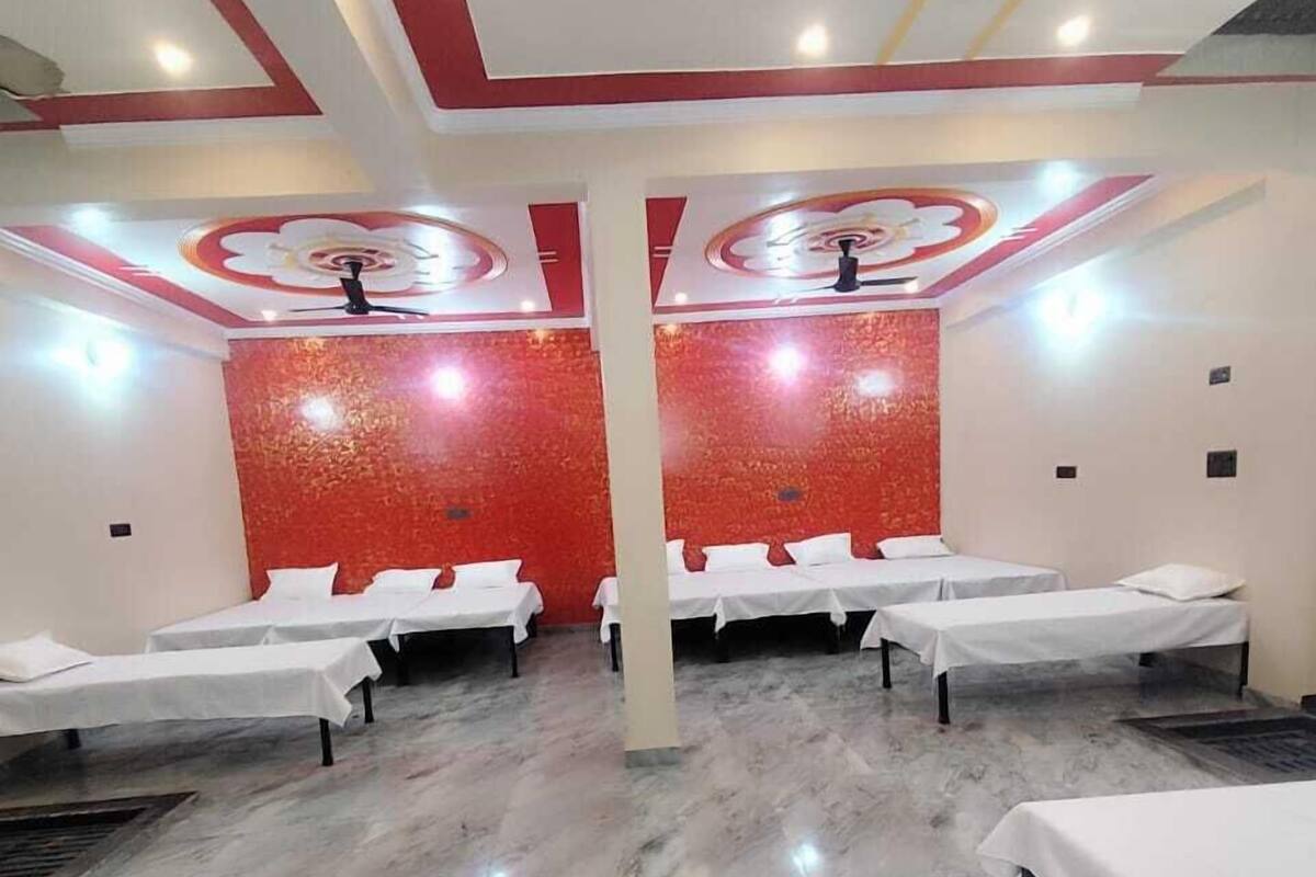Une chambre d’hôtel avec quatre lits alignés, un mur d’accent rouge et un sol en marbre.