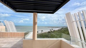 Un'area esterna riparata con vista sul mare, ringhiera in vetro e design architettonico moderno.