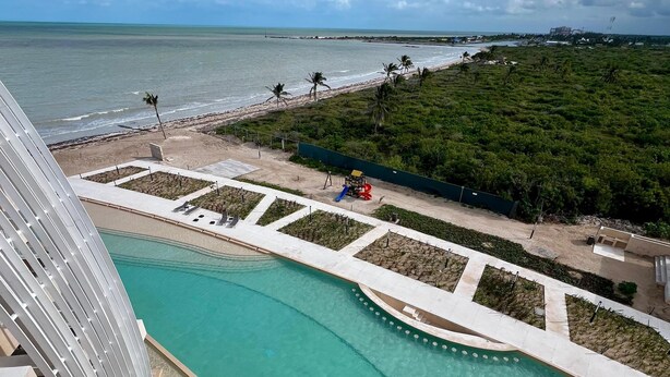 Un resort con una grande piscina, una spiaggia e vista sull'oceano.