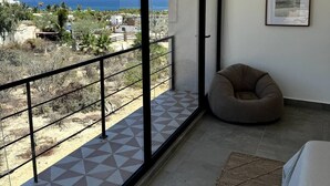 Een balkon met een vloer van geometrische tegels, een kruis kussen en een lijst met een afbeelding.