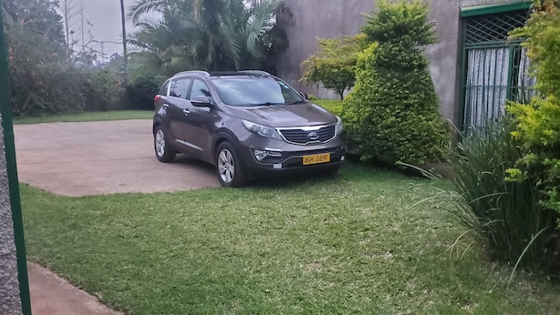 Ein grauer SUV steht auf einer Rasenfläche, im Hintergrund ein Gebäude.