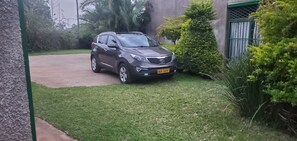 Un SUV gris estacionado en un césped, con un edificio al fondo.