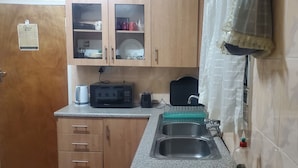 Eine Küche mit Holzausstattung, einer Mikrowelle, einem Toaster und einem Spülbecken.