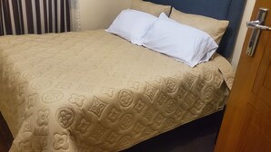Ein Bett mit einer beigen Bettdecke und zwei weißen Kissen.