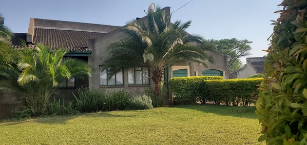 Una casa moderna con un césped cuidado, palmeras y una antena parabólica.