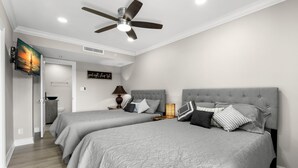 Un dormitorio con dos camas, un ventilador de techo, un televisor y un cartel que dice 'que descanses'.