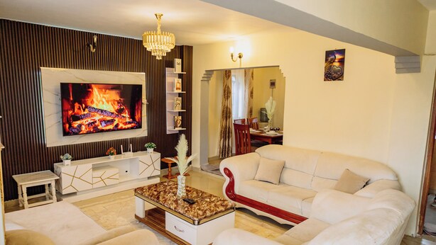 Una sala de estar moderna con televisor de pantalla plana, sofás blancos, una mesa de centro y una chimenea.