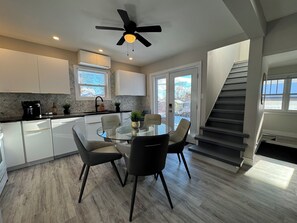 Een moderne keuken met witte kasten, een zwart aanrecht en een glazen eettafel met vier stoelen.