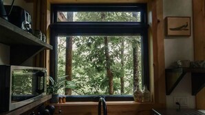 Eine Küche mit einem großen Fenster, einer Spüle und einer Mikrowelle.