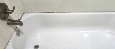 A white bathtub with a single faucet and a drain.