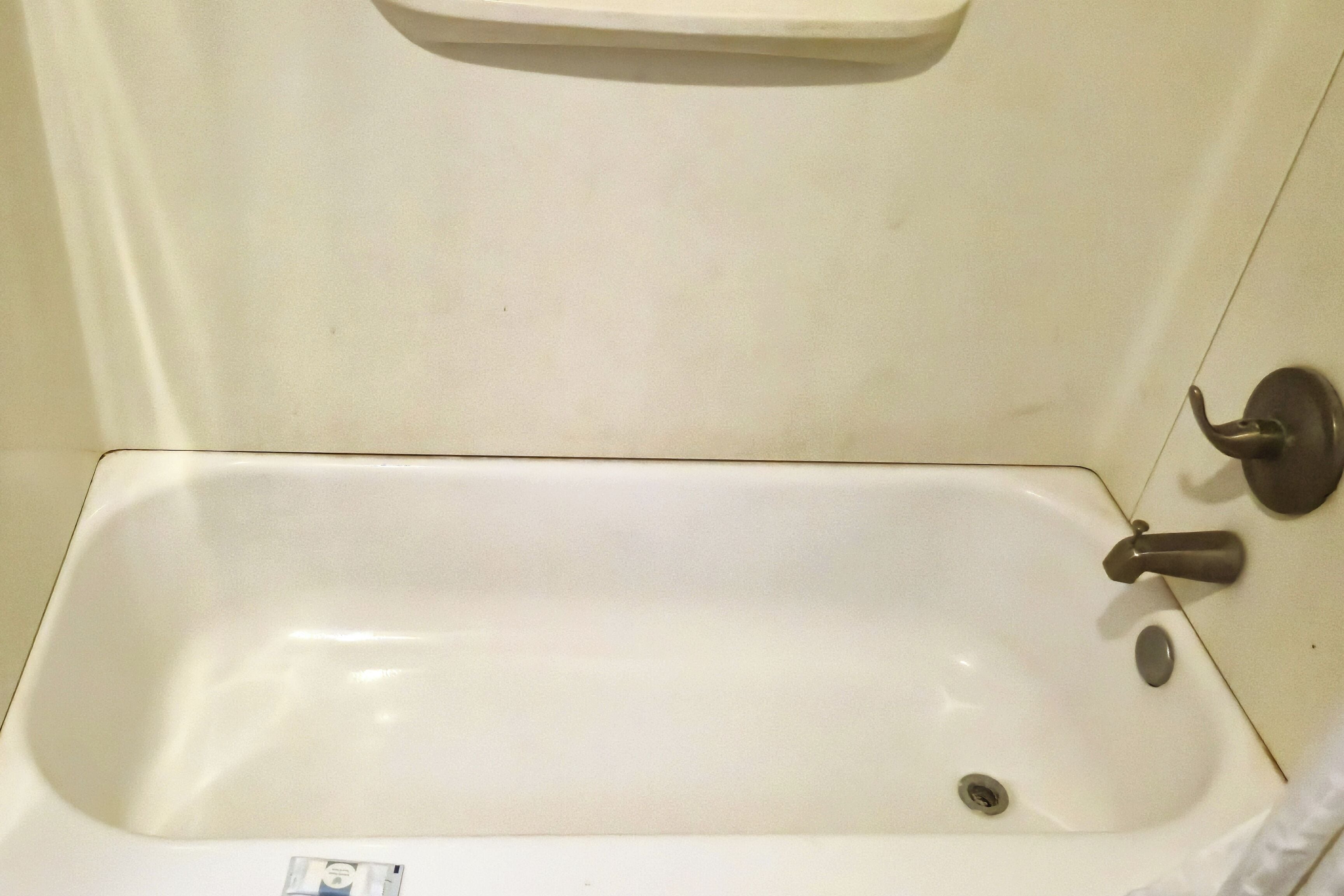 A white bathtub with a single faucet and a drain.