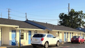 A motel with a row of rooms, each with a blue door and a small window. - Cole Manor Motel By OYO Love Field Market Center (Dallas)