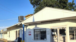 A white building with a single-story structure, a large window, and a door. - Cole Manor Motel By OYO Love Field Market Center (Dallas)
